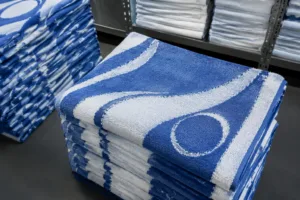 A businesslike view of neatly arranged promotional towels with visible logos, photographed in a factory setting to highlight different branding methods.